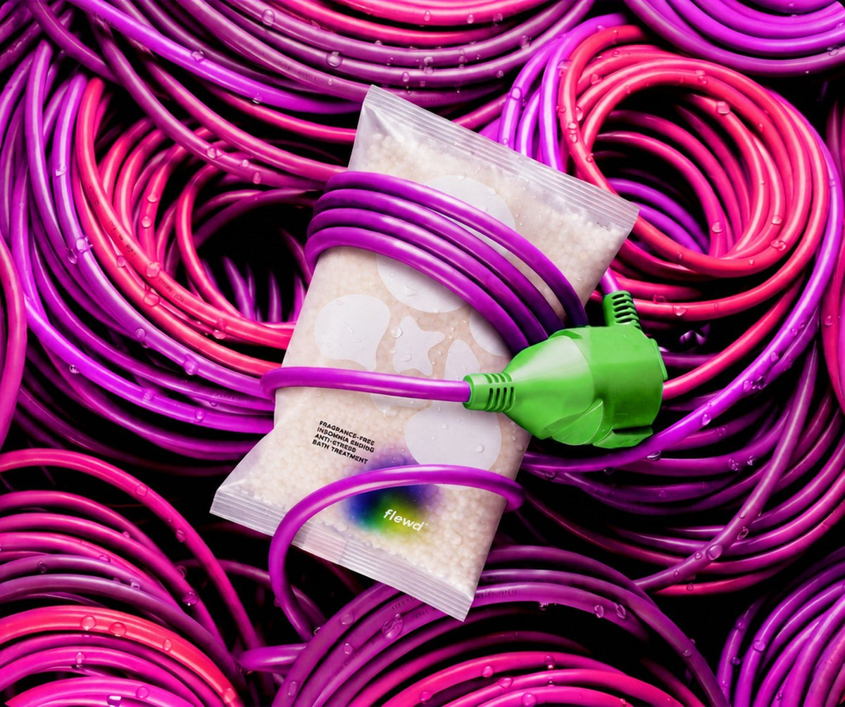 Flewd fragrance-free Insomnia Ending magnesium bath soak clear pouch wrapped in a purple cable with a green plug