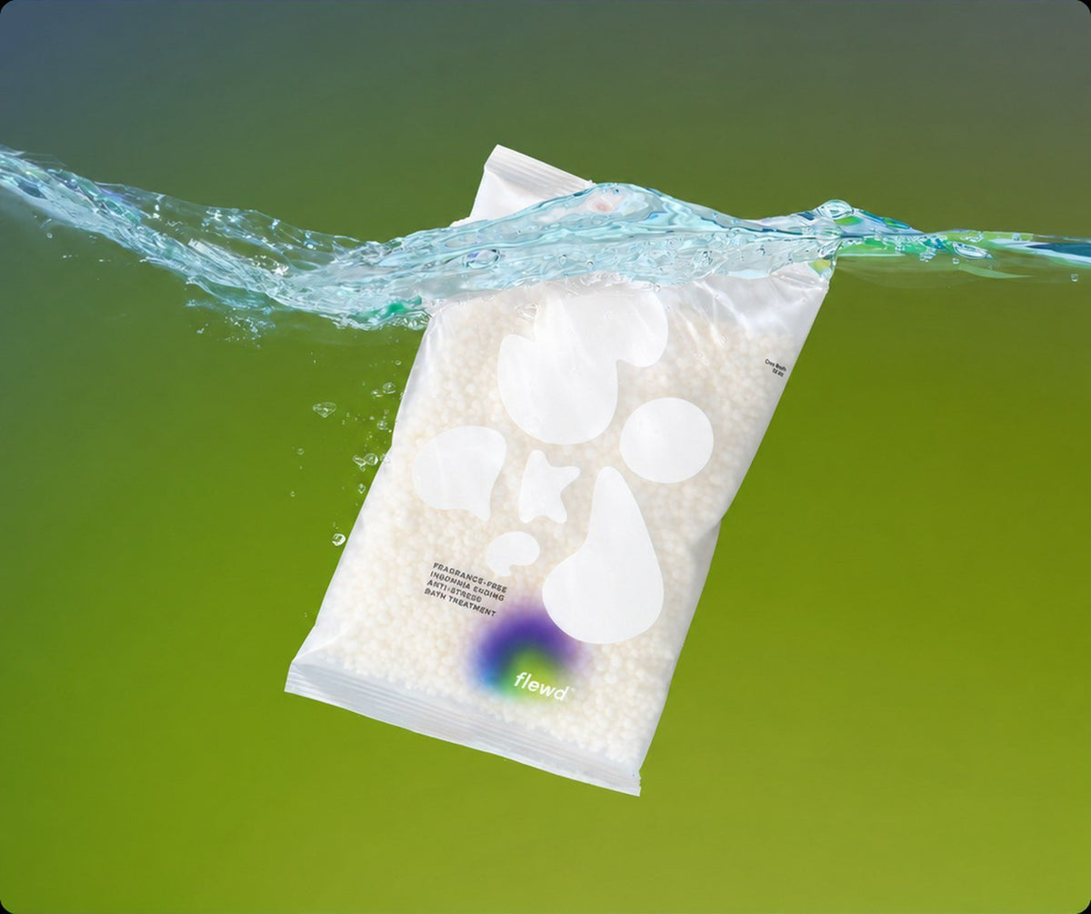 Flewd fragrance-free Insomnia Ending magnesium bath soak clear pouch splashing into water on a green background