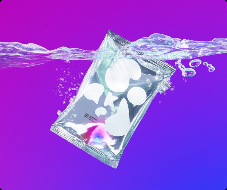 Flewd Rage Squashing magnesium bath soak pouch splashing into water on a purple background